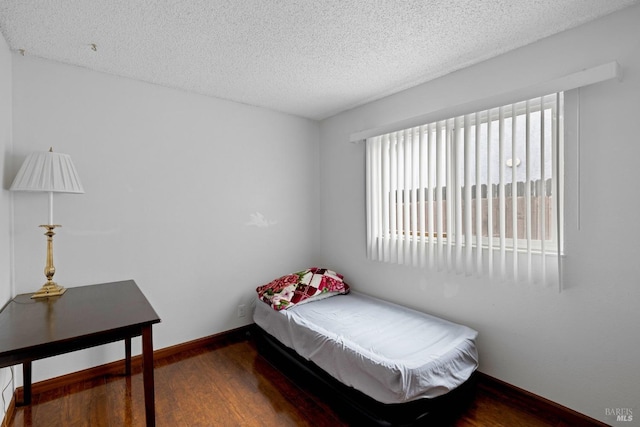 bedroom with baseboards, a textured ceiling, and wood finished floors