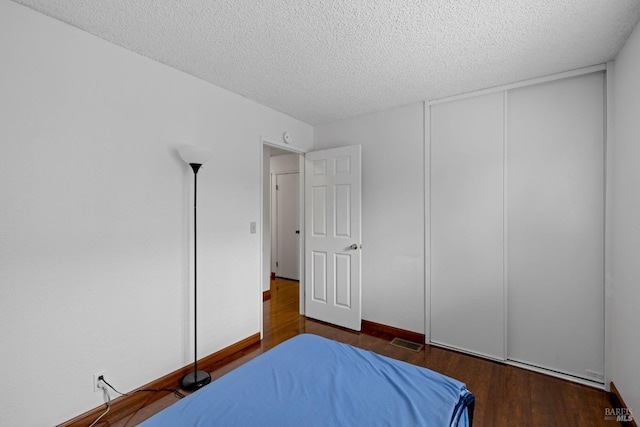 bedroom featuring visible vents, a textured ceiling, wood finished floors, and a closet