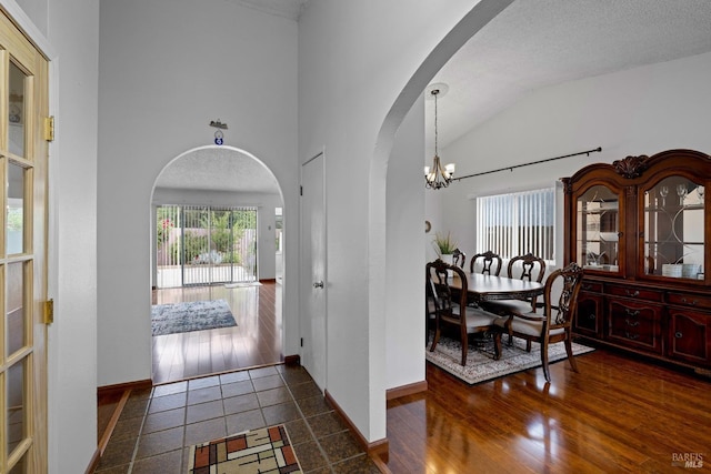 entrance foyer featuring arched walkways, a notable chandelier, a healthy amount of sunlight, and vaulted ceiling