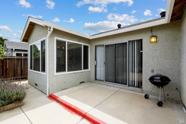 rear view of property featuring a patio, fence, and stucco siding