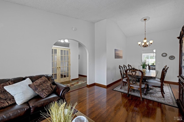 dining area featuring arched walkways, vaulted ceiling, wood finished floors, and an inviting chandelier