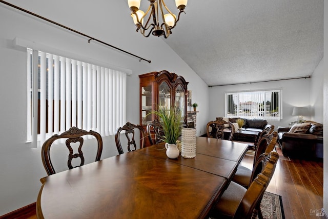 dining area featuring a textured ceiling, a chandelier, vaulted ceiling, and dark wood-type flooring