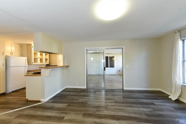 kitchen with kitchen peninsula, white refrigerator, and dark hardwood / wood-style flooring