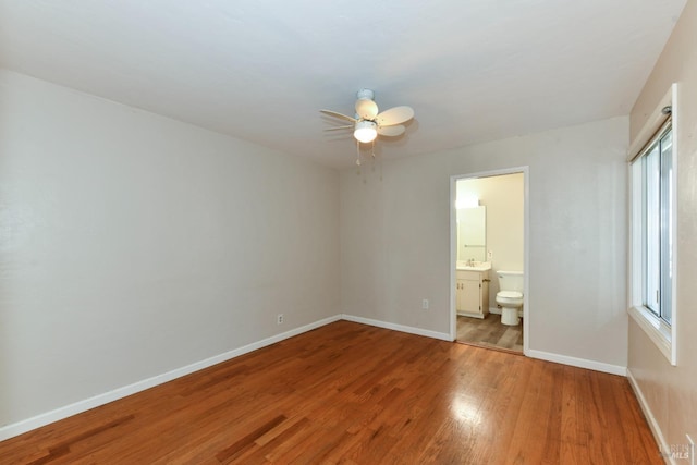 unfurnished bedroom featuring ceiling fan, connected bathroom, wood-type flooring, and sink