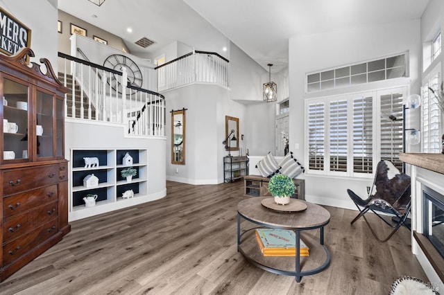 living room with a high ceiling, an inviting chandelier, and wood-type flooring