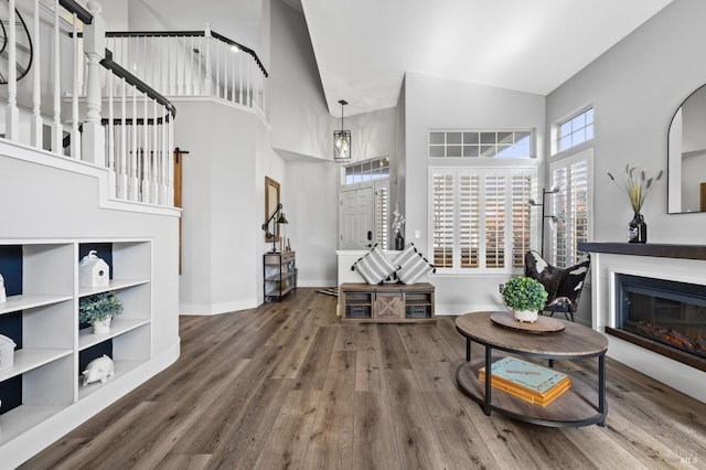 living room with built in features, a towering ceiling, and hardwood / wood-style flooring