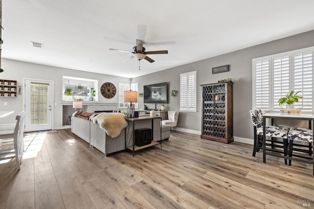 living room featuring a wealth of natural light, ceiling fan, and light hardwood / wood-style floors