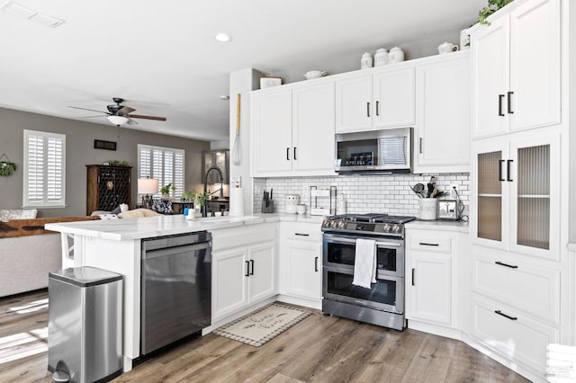 kitchen with white cabinets, kitchen peninsula, sink, and appliances with stainless steel finishes