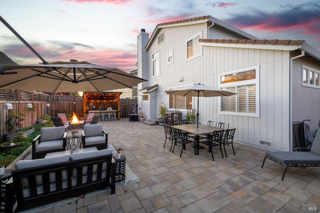 patio terrace at dusk featuring an outdoor living space with a fire pit