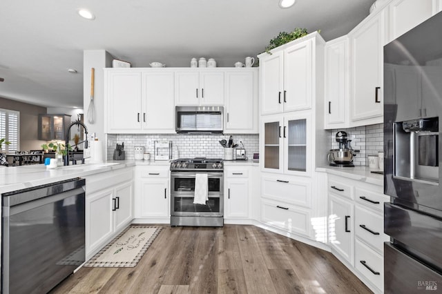 kitchen featuring light stone countertops, sink, tasteful backsplash, white cabinets, and black appliances