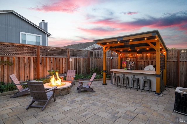 patio terrace at dusk featuring an outdoor bar, an outdoor fire pit, and central air condition unit