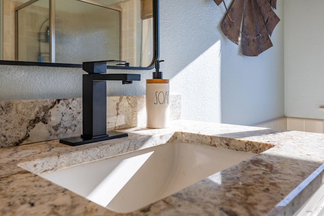 interior details featuring a shower with door and sink