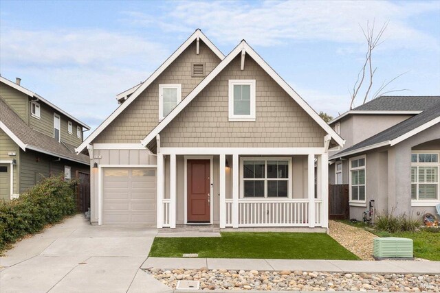 craftsman-style home featuring a front lawn, covered porch, and a garage