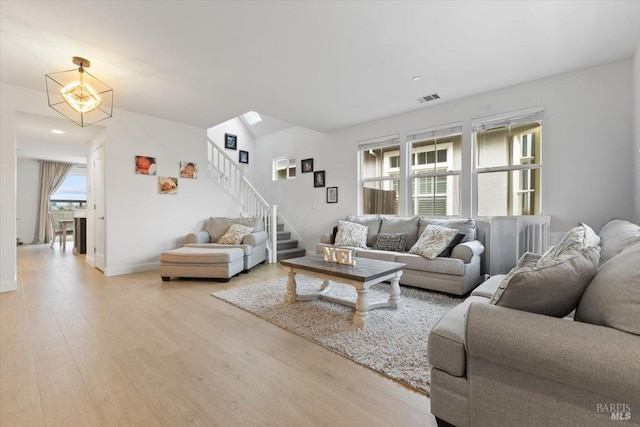 living area with visible vents, stairway, baseboards, and wood finished floors