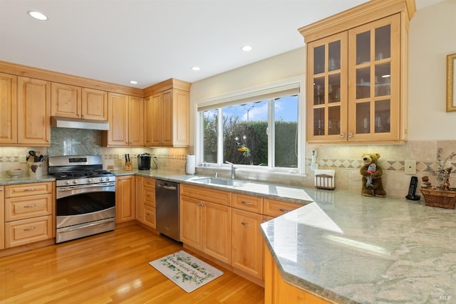 kitchen with sink, light hardwood / wood-style flooring, decorative backsplash, appliances with stainless steel finishes, and light stone counters