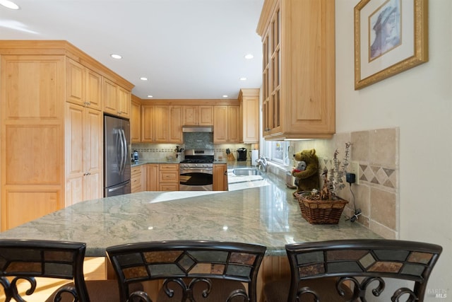 kitchen featuring sink, a breakfast bar area, tasteful backsplash, kitchen peninsula, and stainless steel appliances