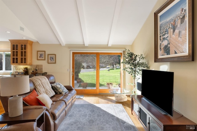 living room featuring lofted ceiling with beams and light hardwood / wood-style flooring