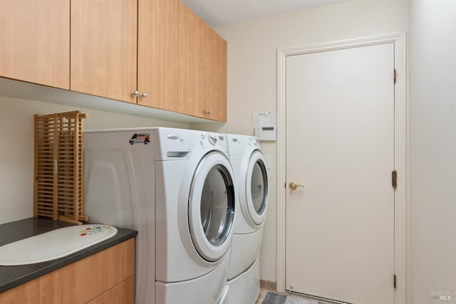 laundry room featuring washer and clothes dryer and cabinets