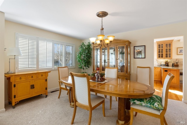 dining room with light carpet and a notable chandelier