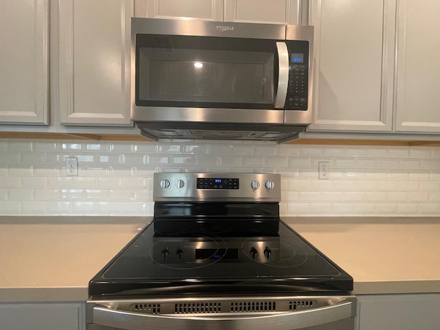 kitchen with gray cabinets, stainless steel appliances, and decorative backsplash