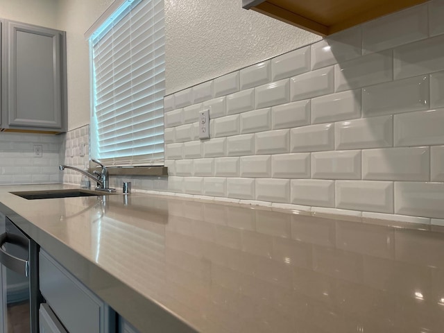 room details featuring sink, gray cabinets, and decorative backsplash