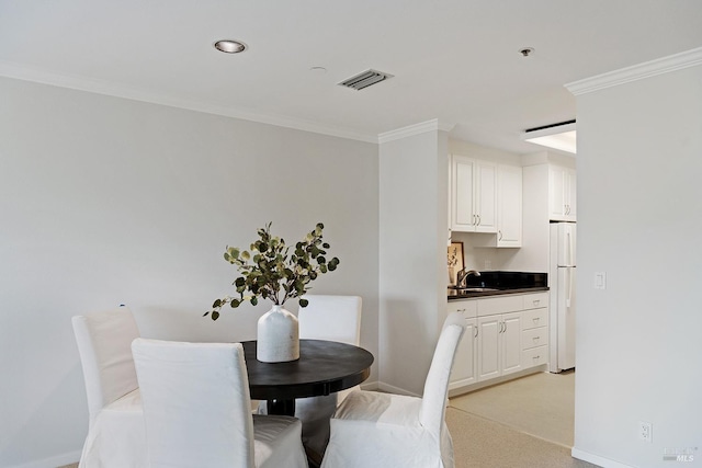 carpeted dining area with crown molding and sink