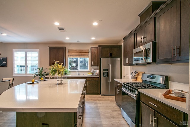 kitchen featuring sink, light hardwood / wood-style flooring, dark brown cabinets, a kitchen island, and stainless steel appliances