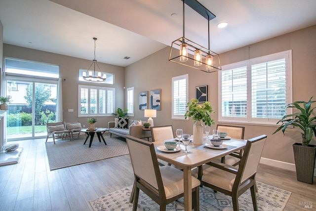 dining room with a notable chandelier, a healthy amount of sunlight, and wood-type flooring