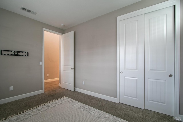 unfurnished bedroom featuring dark carpet and a closet