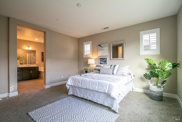 carpeted bedroom featuring multiple windows and ensuite bathroom