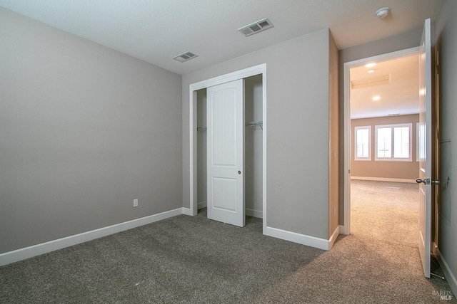 unfurnished bedroom featuring visible vents, baseboards, and dark colored carpet
