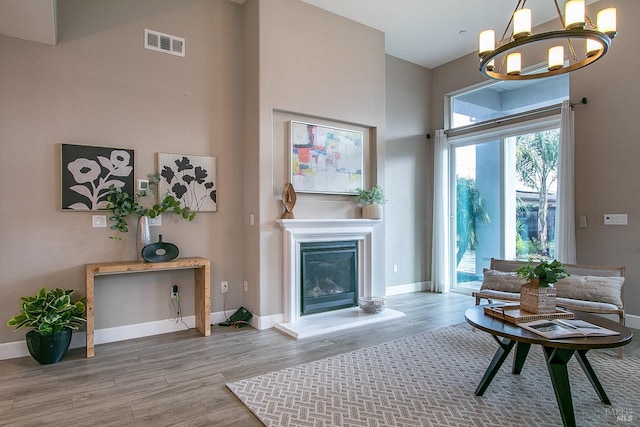 living room with light hardwood / wood-style floors, a high ceiling, and an inviting chandelier