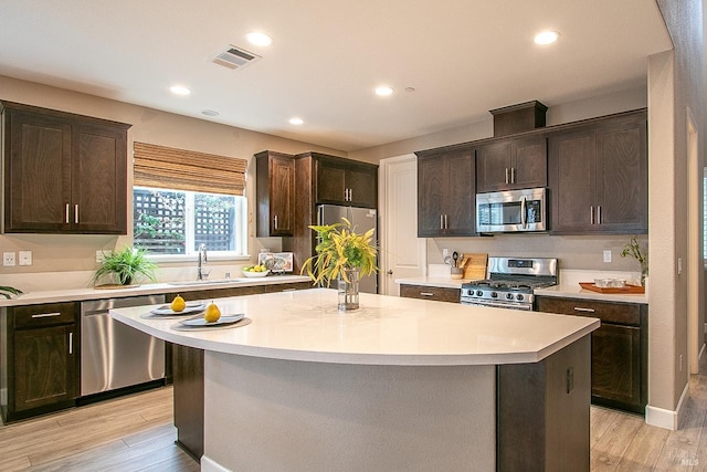 kitchen featuring appliances with stainless steel finishes, light hardwood / wood-style flooring, a kitchen island, and sink