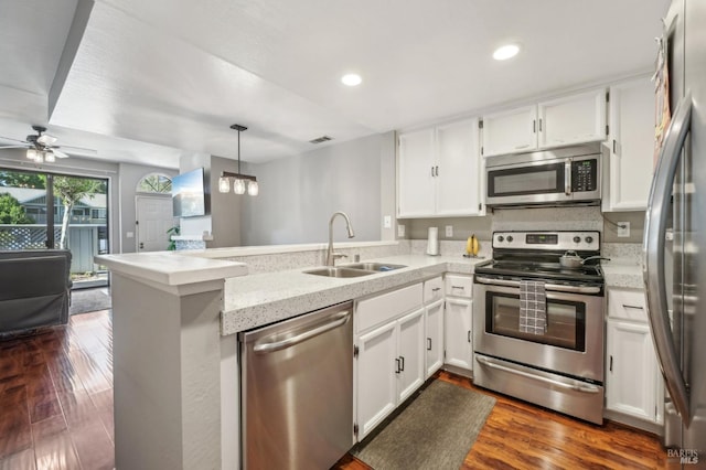 kitchen with appliances with stainless steel finishes, pendant lighting, white cabinetry, sink, and kitchen peninsula