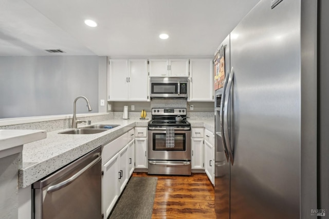 kitchen with sink, appliances with stainless steel finishes, white cabinetry, dark hardwood / wood-style flooring, and kitchen peninsula