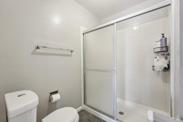 bathroom featuring a shower with shower door and toilet