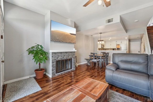 living room featuring ceiling fan, a fireplace, and dark hardwood / wood-style flooring