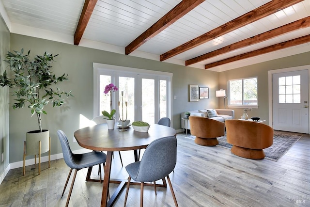 dining room featuring light wood-style floors, french doors, beamed ceiling, and baseboards