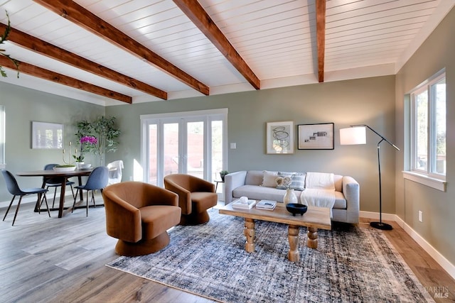 living area with beam ceiling, baseboards, wood finished floors, and french doors