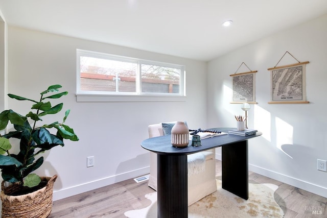 home office with light wood-style flooring and baseboards