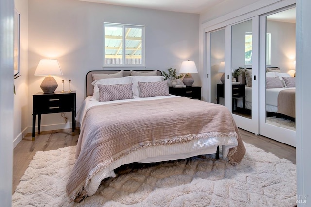 bedroom featuring french doors, multiple windows, wood finished floors, and baseboards