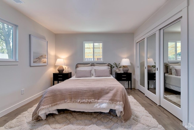 bedroom featuring light wood-type flooring, a closet, and baseboards