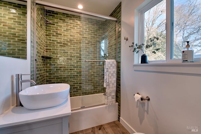 bathroom with enclosed tub / shower combo, wood finished floors, and vanity