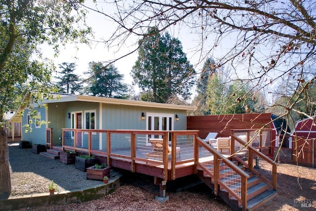 rear view of property with a wooden deck, fence, and french doors