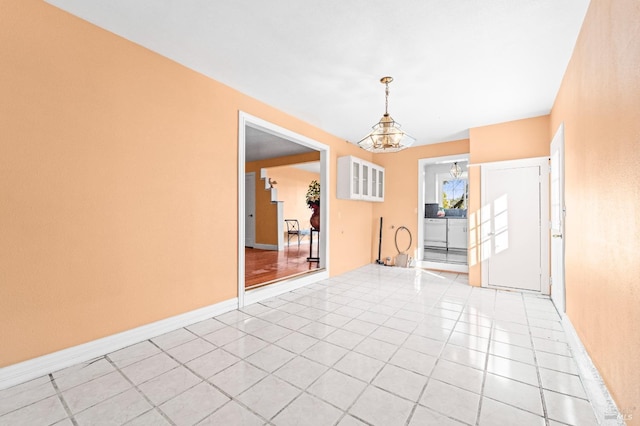 tiled empty room featuring a chandelier