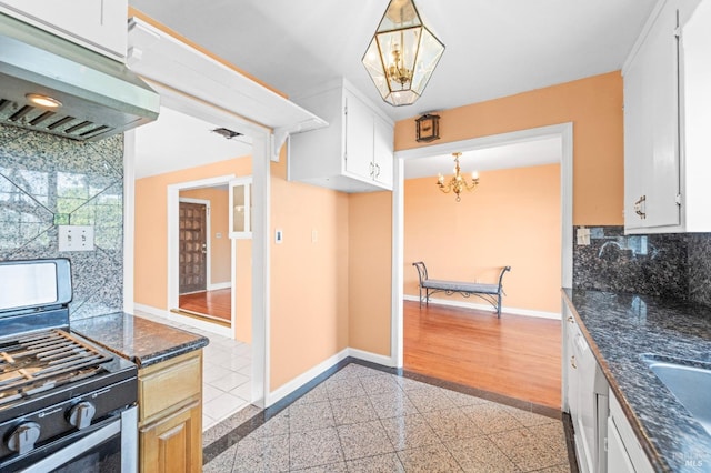 kitchen with granite finish floor, baseboards, under cabinet range hood, and stainless steel gas range oven