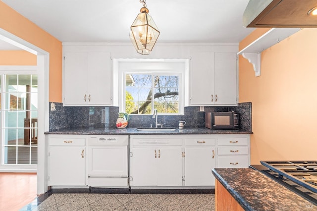 kitchen featuring white cabinets, white dishwasher, hanging light fixtures, and sink