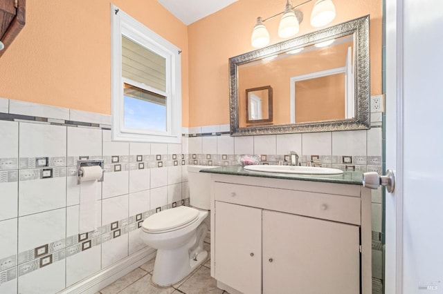 half bath featuring toilet, tile walls, vanity, and tile patterned flooring