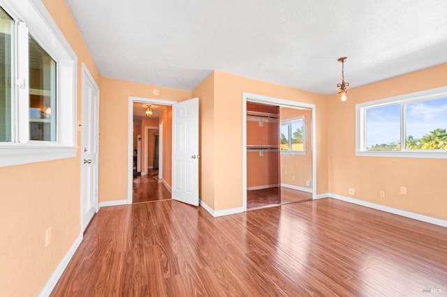 unfurnished bedroom with a closet, baseboards, and wood finished floors