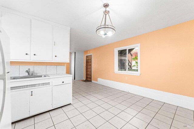 kitchen featuring decorative backsplash, sink, white cabinets, and hanging light fixtures